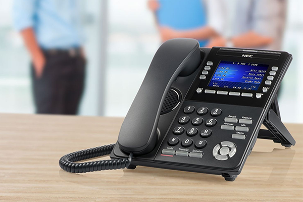NEC PBX Phone on a desk with people talking in the background